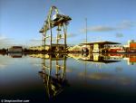 ID 1855 PORT OF AUCKLAND, NZ - The oldest crane at the port, originally operating at the Axis Fergusson Terminal, is reflected in the surface flooding left by heavy overnight rains as it is carefully...